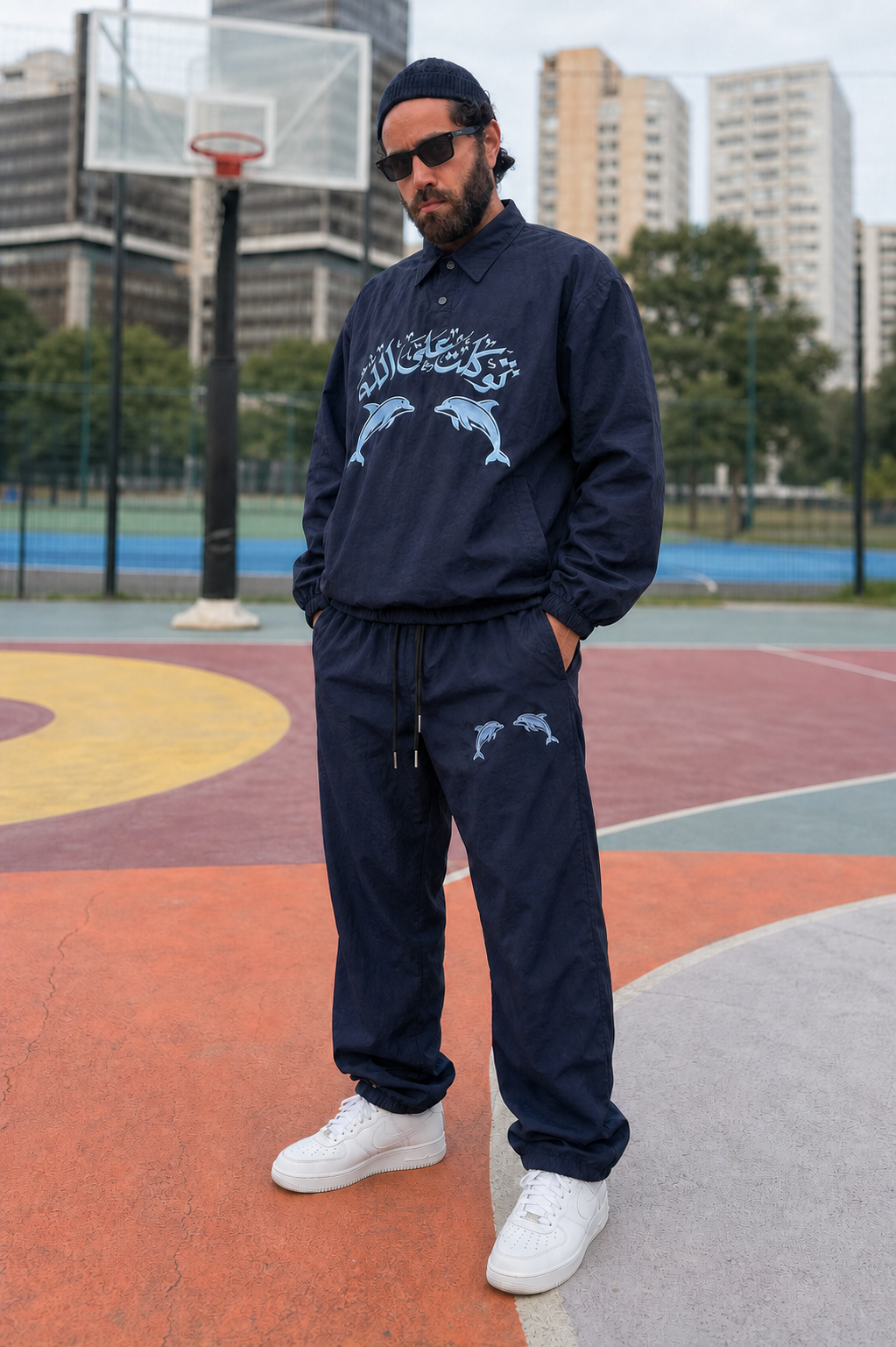 Ensemble survêtement bleu nuit brodé de dauphins et de calligraphie arabe, porté sur un terrain de basket